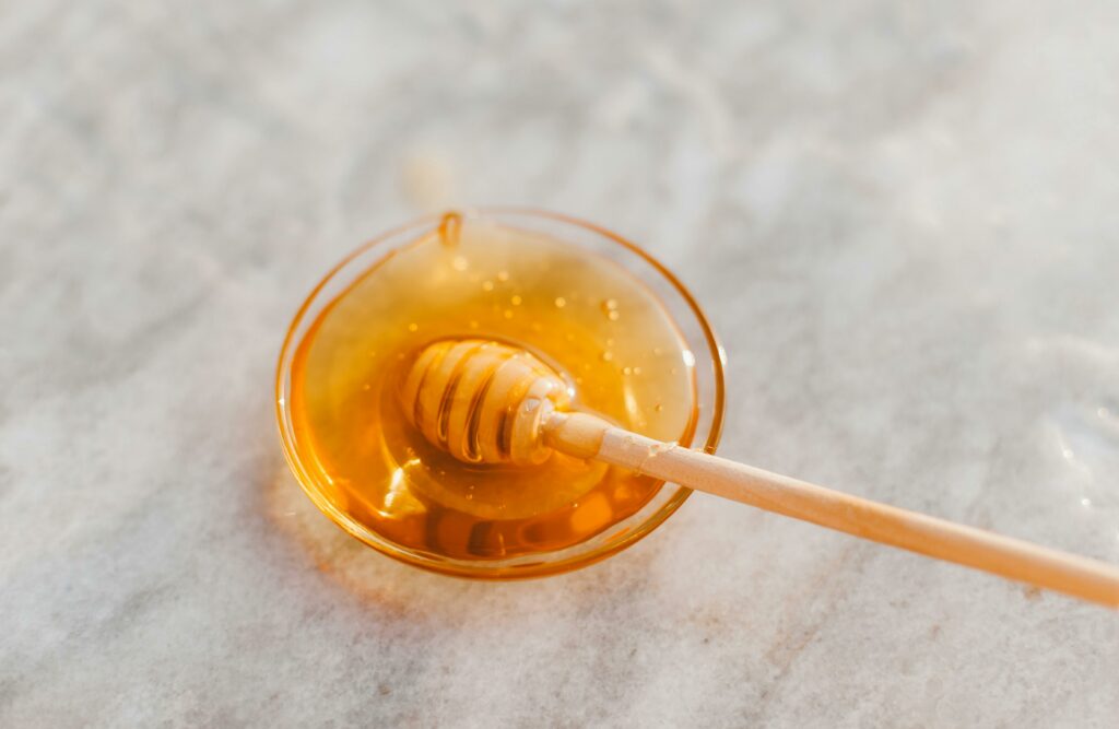 pexels-photo-6422029-6422029-1 A close-up shot of a honey dripper resting in a glass bowl filled with golden honey.